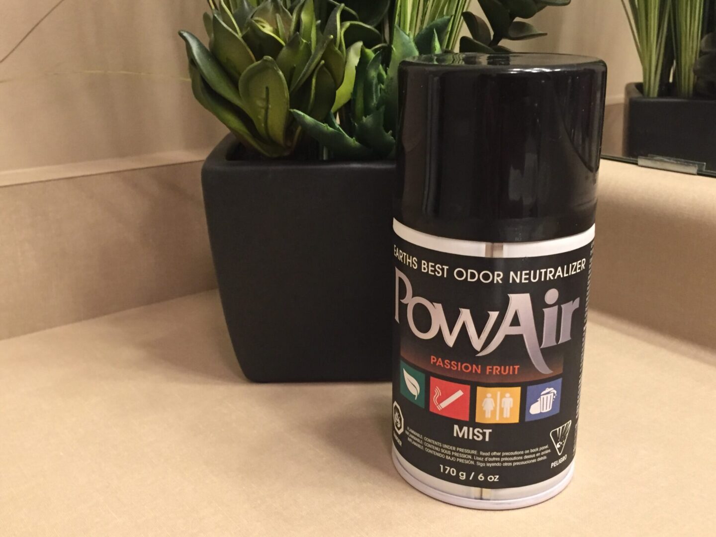 A can of powair on the table next to a plant.